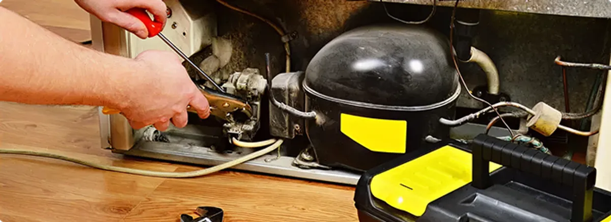 Refrigerator repair technician fixing the compressor and wiring in Portland, OR